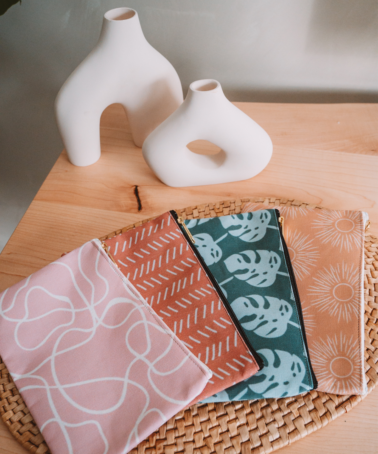 All accessory pouches are laying on a desk with two asymmetrical vases in the background