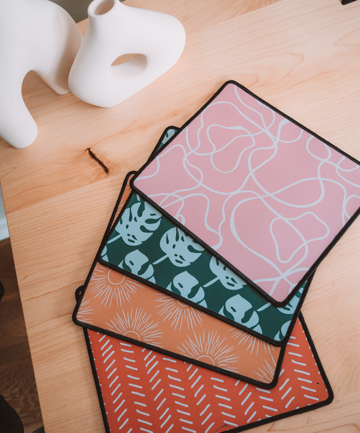 All mousepads are laying on the desk. In order: Terrain, Monstera, Soleil, and Harrow.