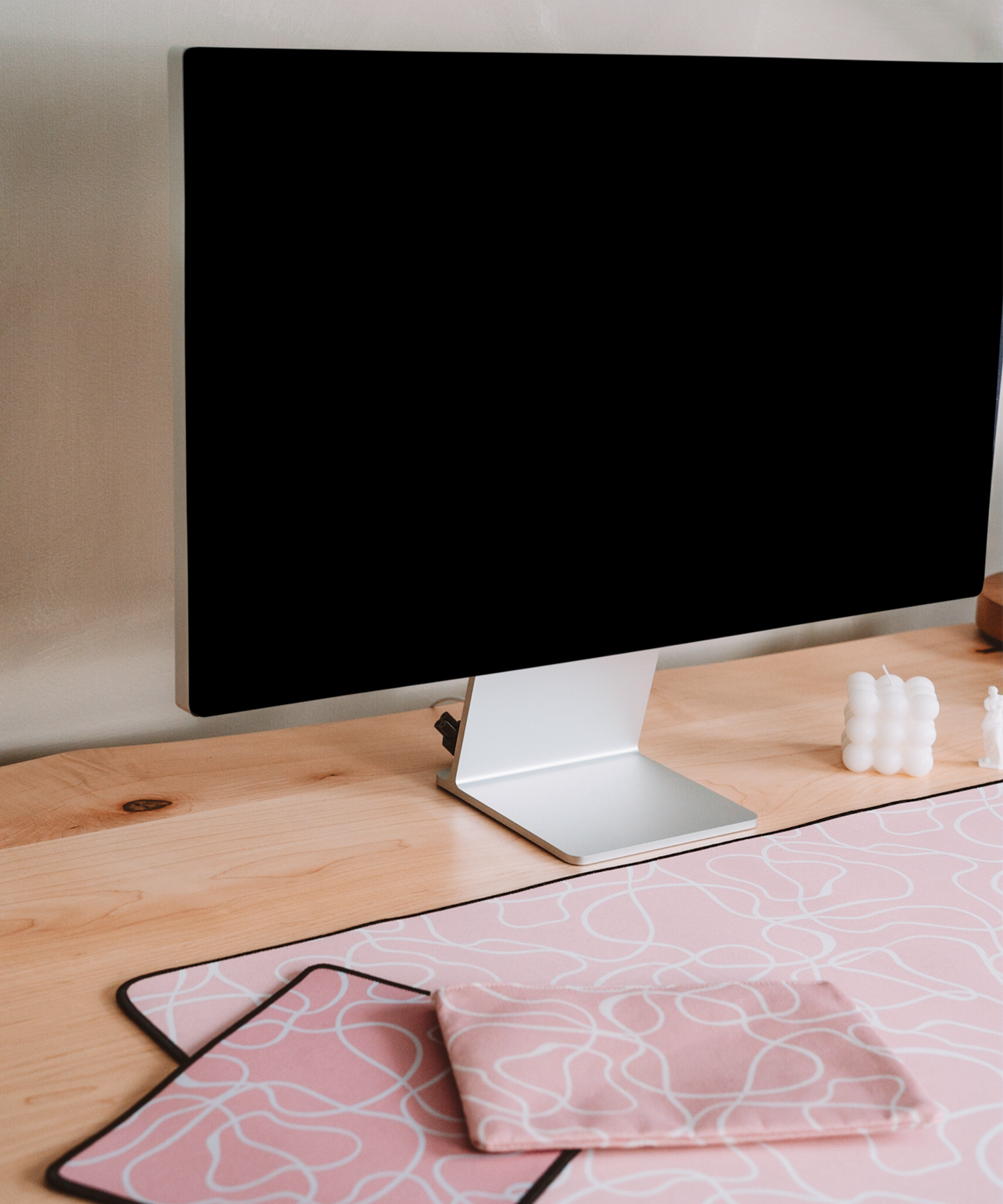 The Terrain mousepad, Terrain accessory pouch, and Terrain desk mat are laying on a desk underneath the Apple Studio Display.