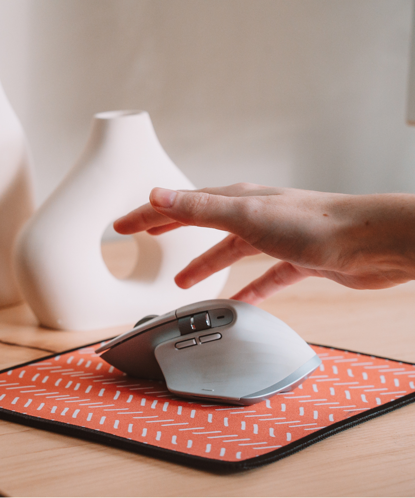 A hand is grabbing for a mouse on top of the Harrow mousepad