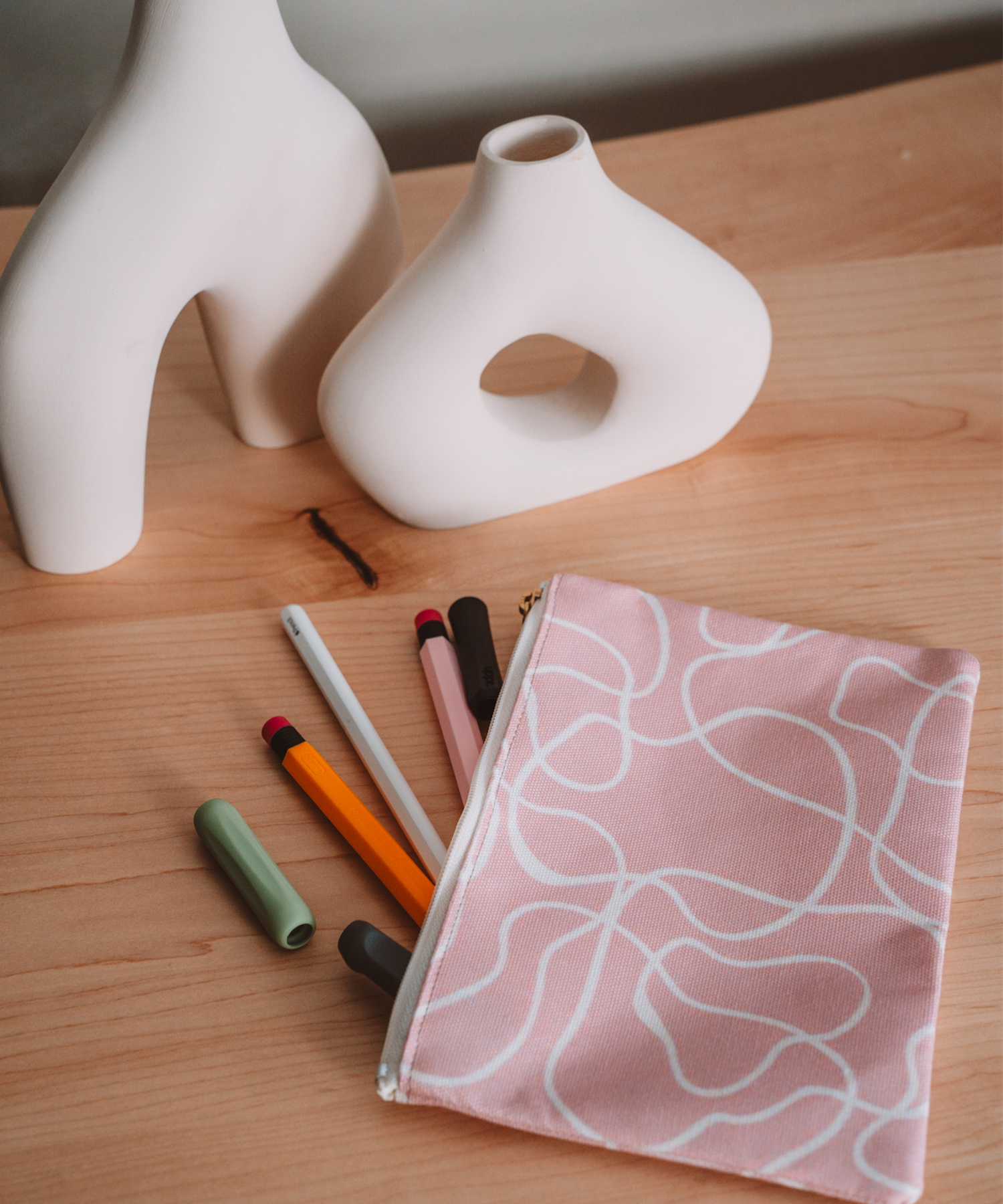 The Terrain accessory pouch is laying on a desk with Apple Pencil accessories spilling out. In the background are two asymmetrical vases.
