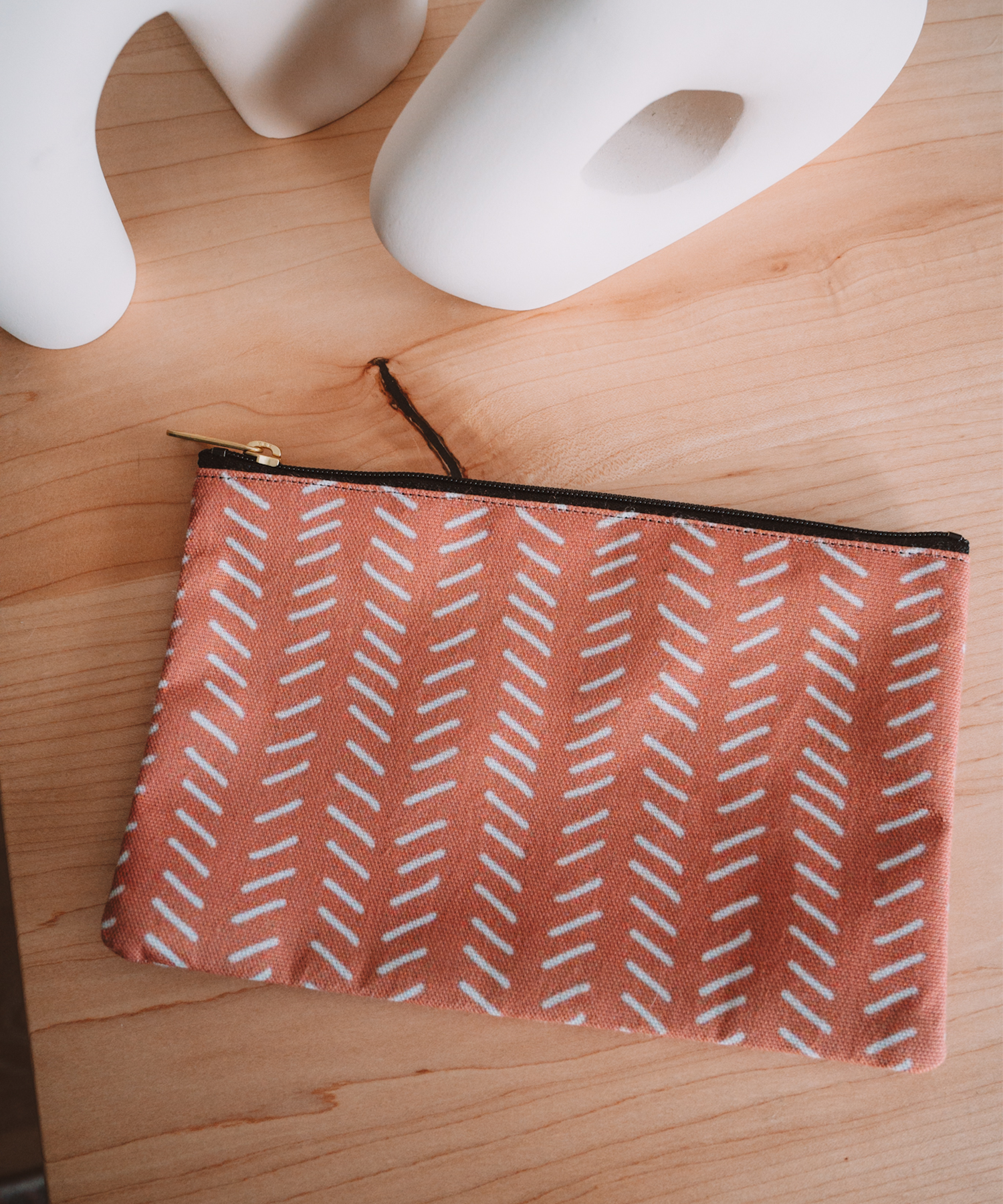 The Harrow accessory pouch is laying on a desk with two asymmetrical vases in the vackground