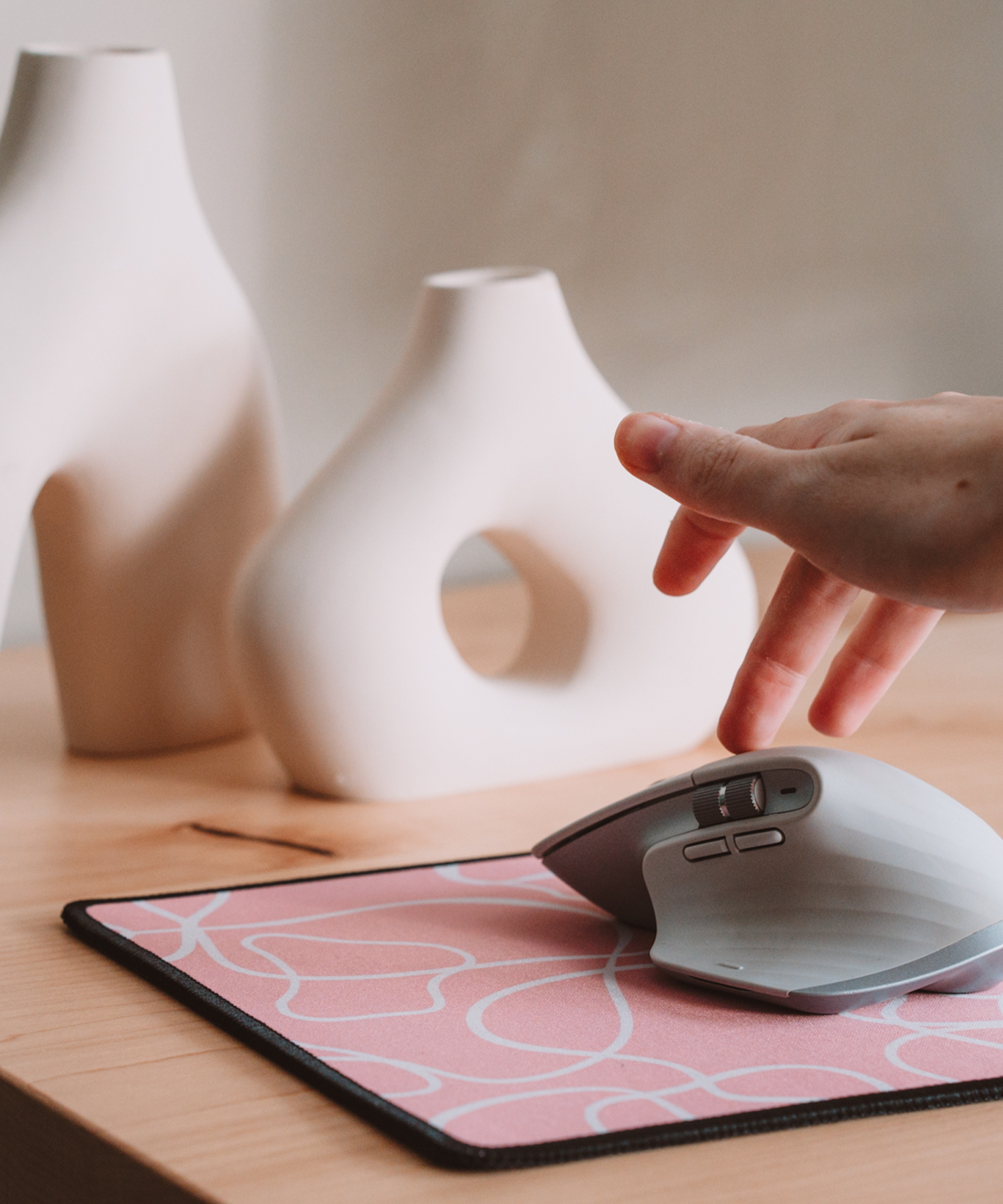 A hand reaching for a mouse on top of the Terrain mousepad. In the background are two asymmetrical vases.