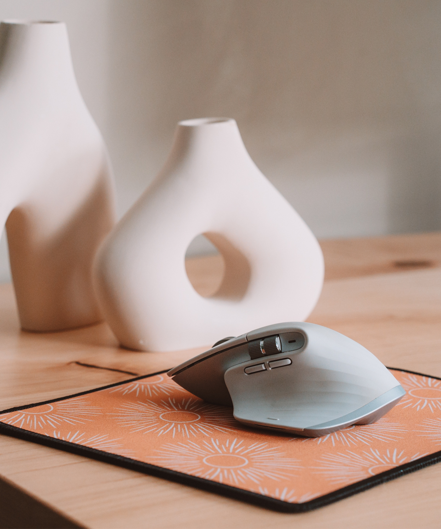 A mouse is sitting on top of the Soleil mousepad with two asymmetrical vases in the background