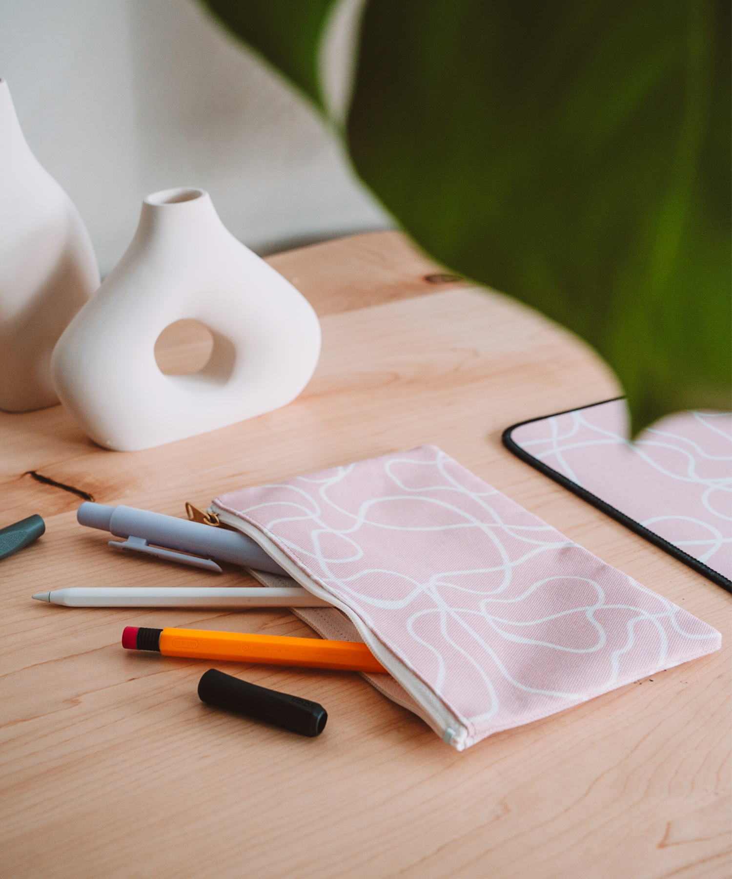 The Terrain accessory pouch is spilling out Apple Pencil accessories on a desk with two asymmetrical vases in the background