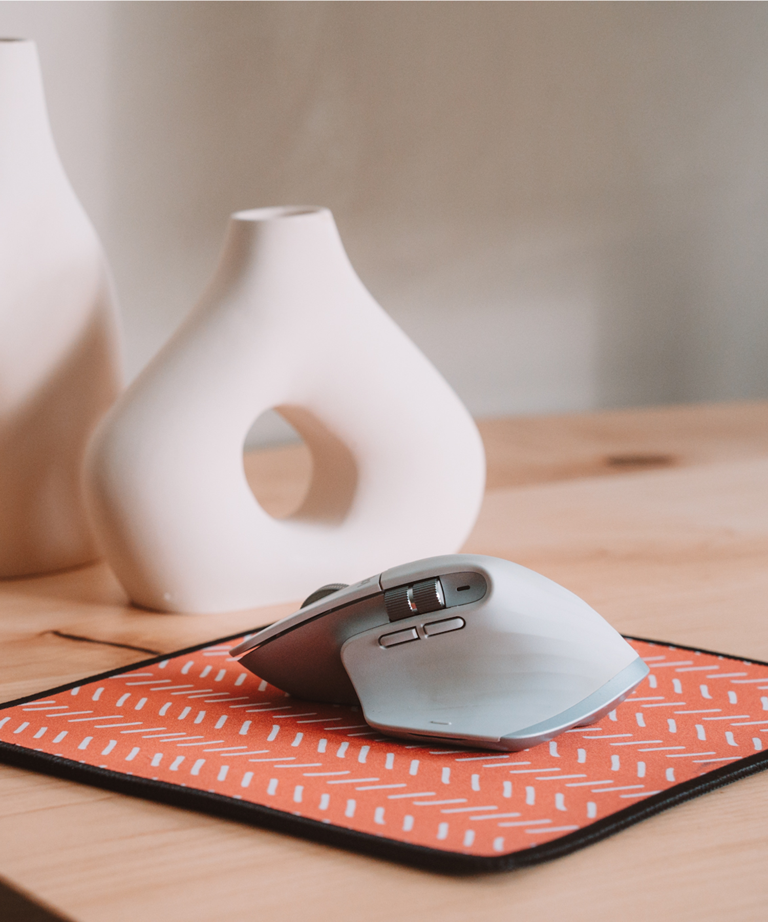A mouse sitting on top of the Harrow mousepad. In the background, there is an asymmetrical vase.