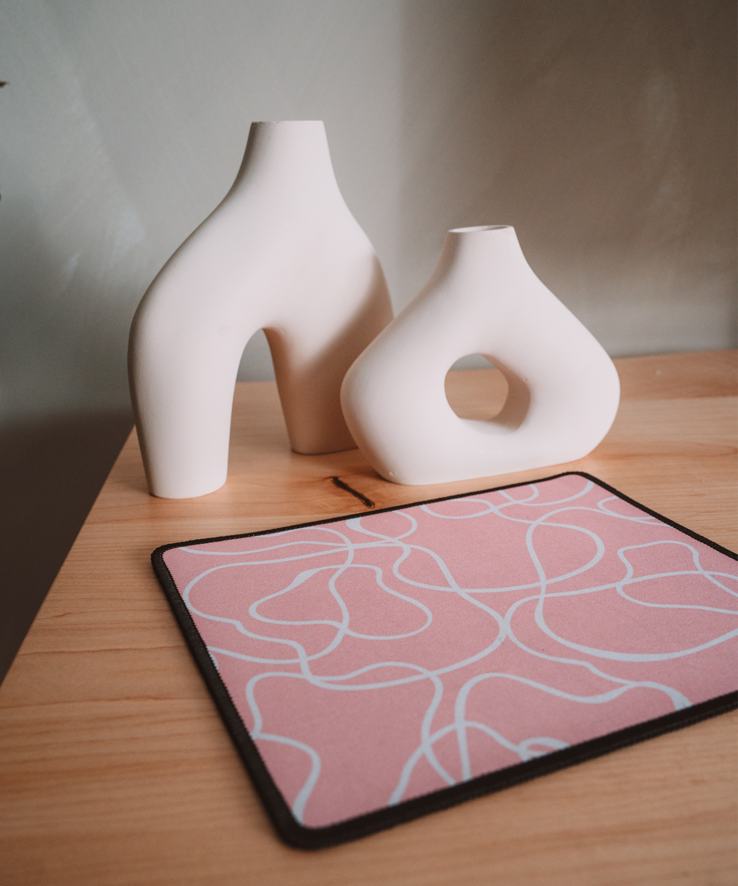 The Terrain mousepad laying on a desk with two asymmetrical vases in the background