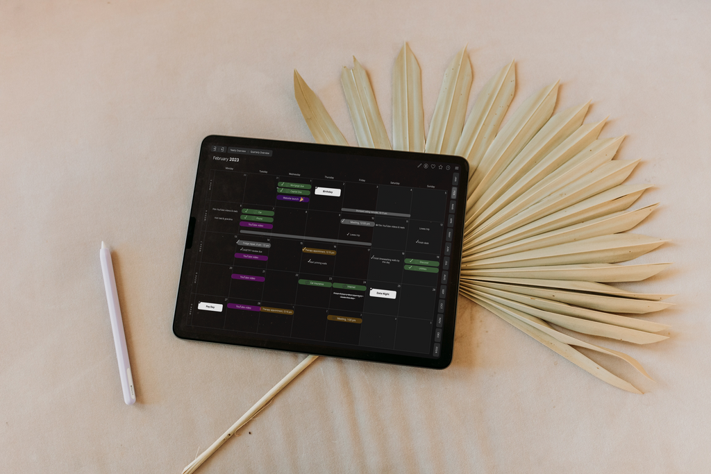 The dark mode version of the Cyberry digital planner monthly page is featured. Next to it is an Apple Pencil and boho leaf fan.