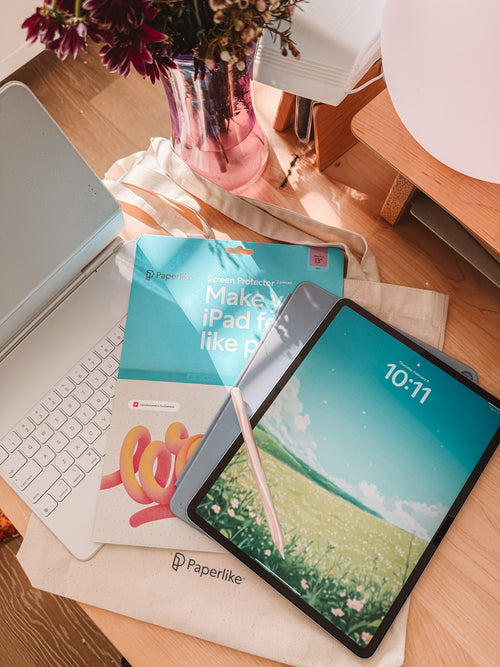 Tablet with screen protector on a desk next to a laptop and books